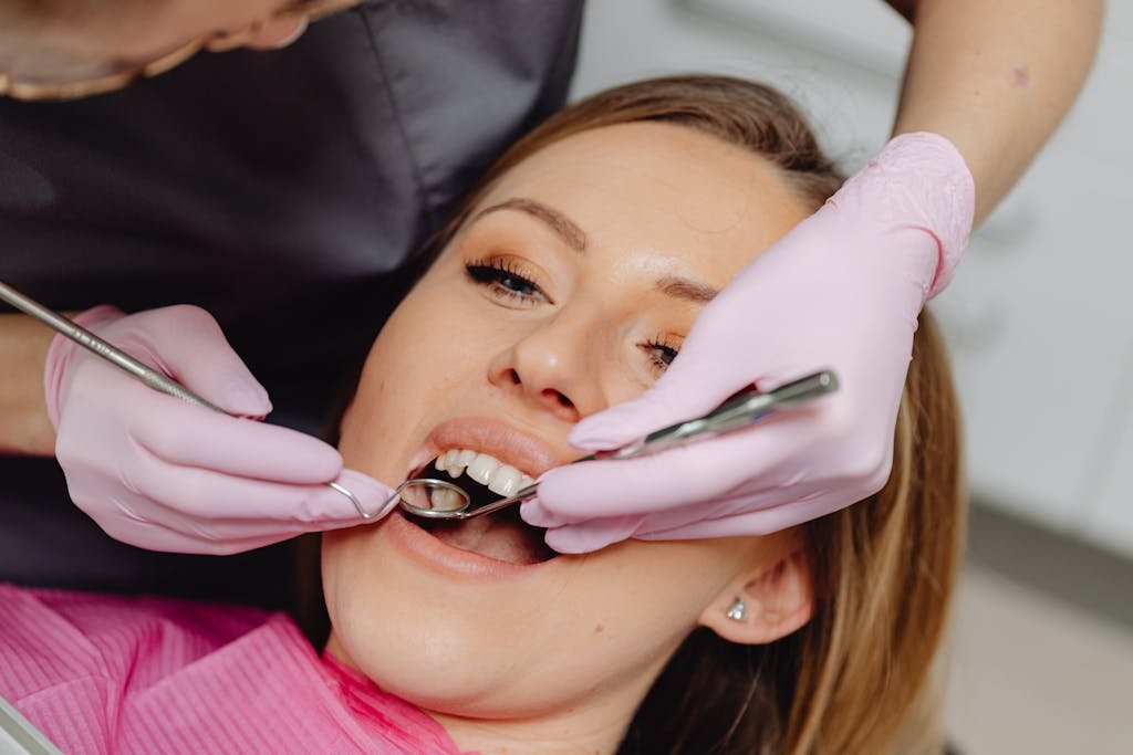 Female patient receiving a dental examination with instruments at a clinic.